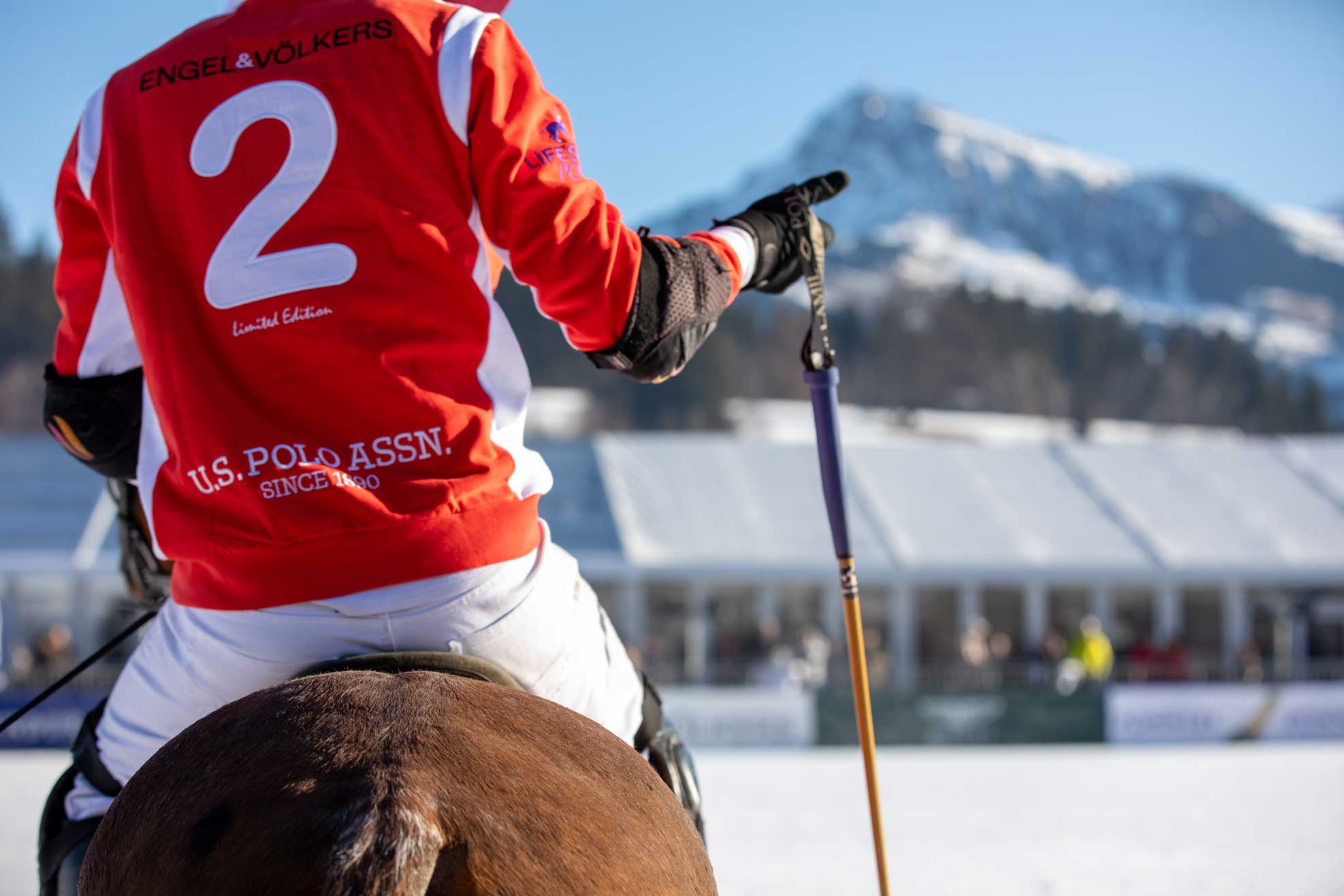 Snow Polo Reiter von hinten mit rotem Polo Shirt mit weißer 2 auf dem Rücken